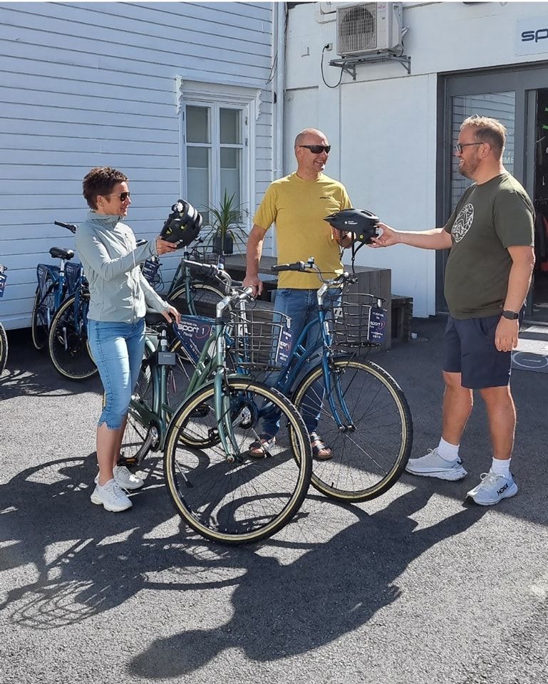 Sykkelutleie - Mandal - Sport1
tre smilende personer prater sammen, en mann gir hjelm til to som skal sykle