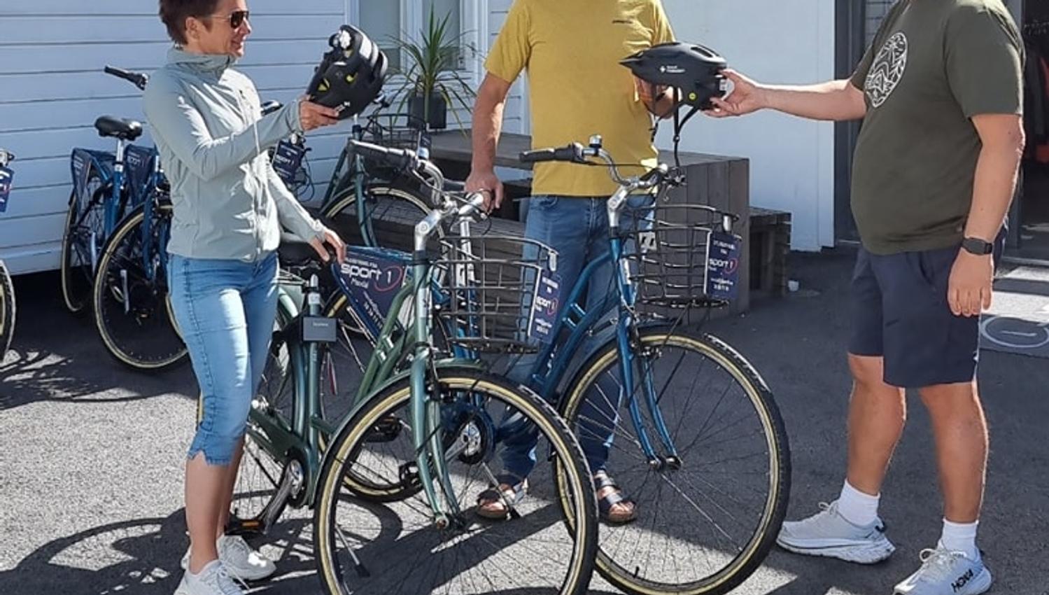 Sykkelutleie - Mandal - Sport1
tre smilende personer prater sammen, en mann gir hjelm til to som skal sykle