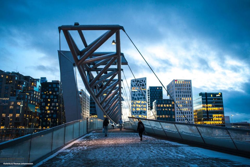 A few people walking alongside the bridge towards Barcode.