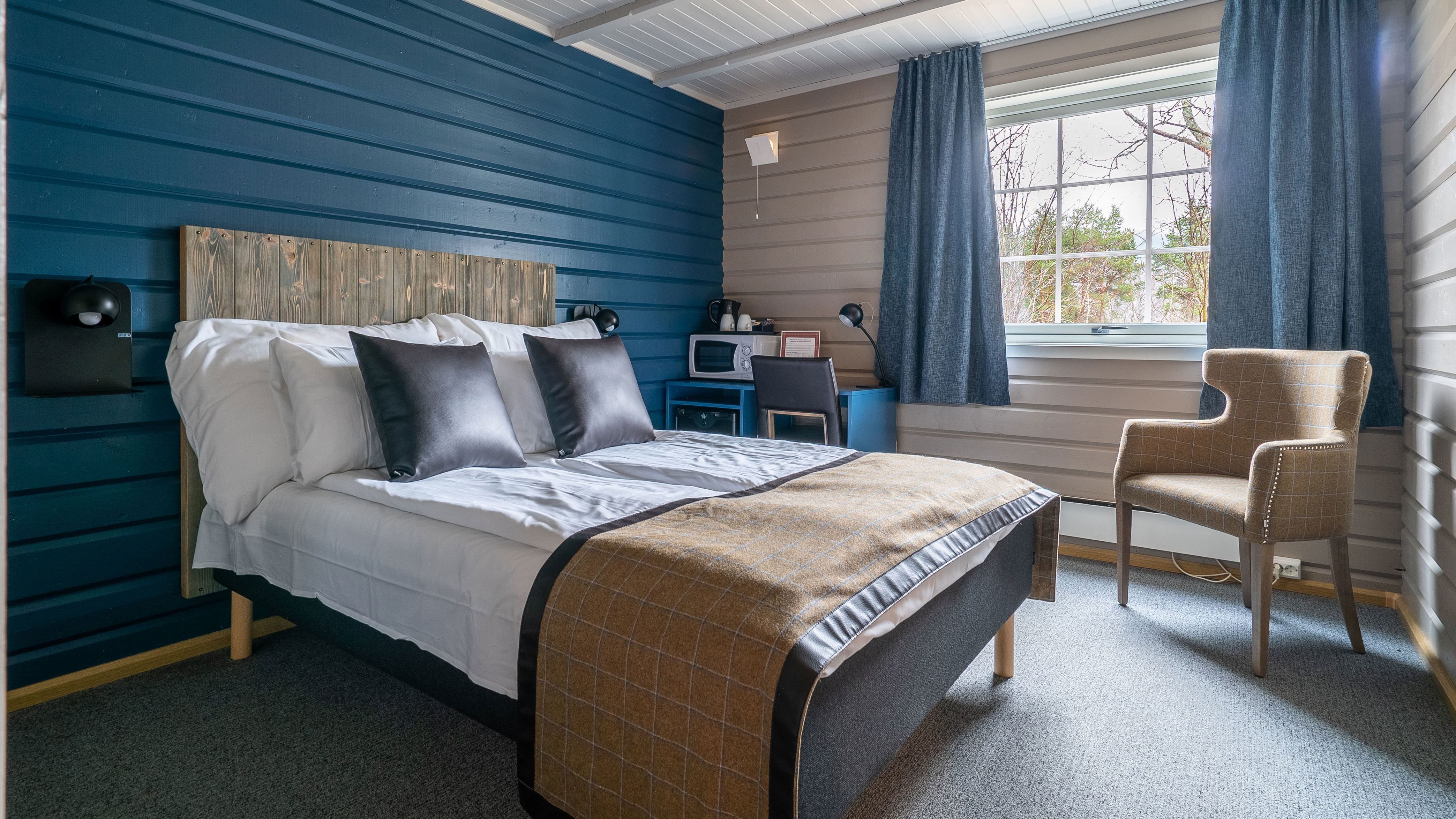 Bedroom with bed, blue curtains, desk, and two-tone walls
