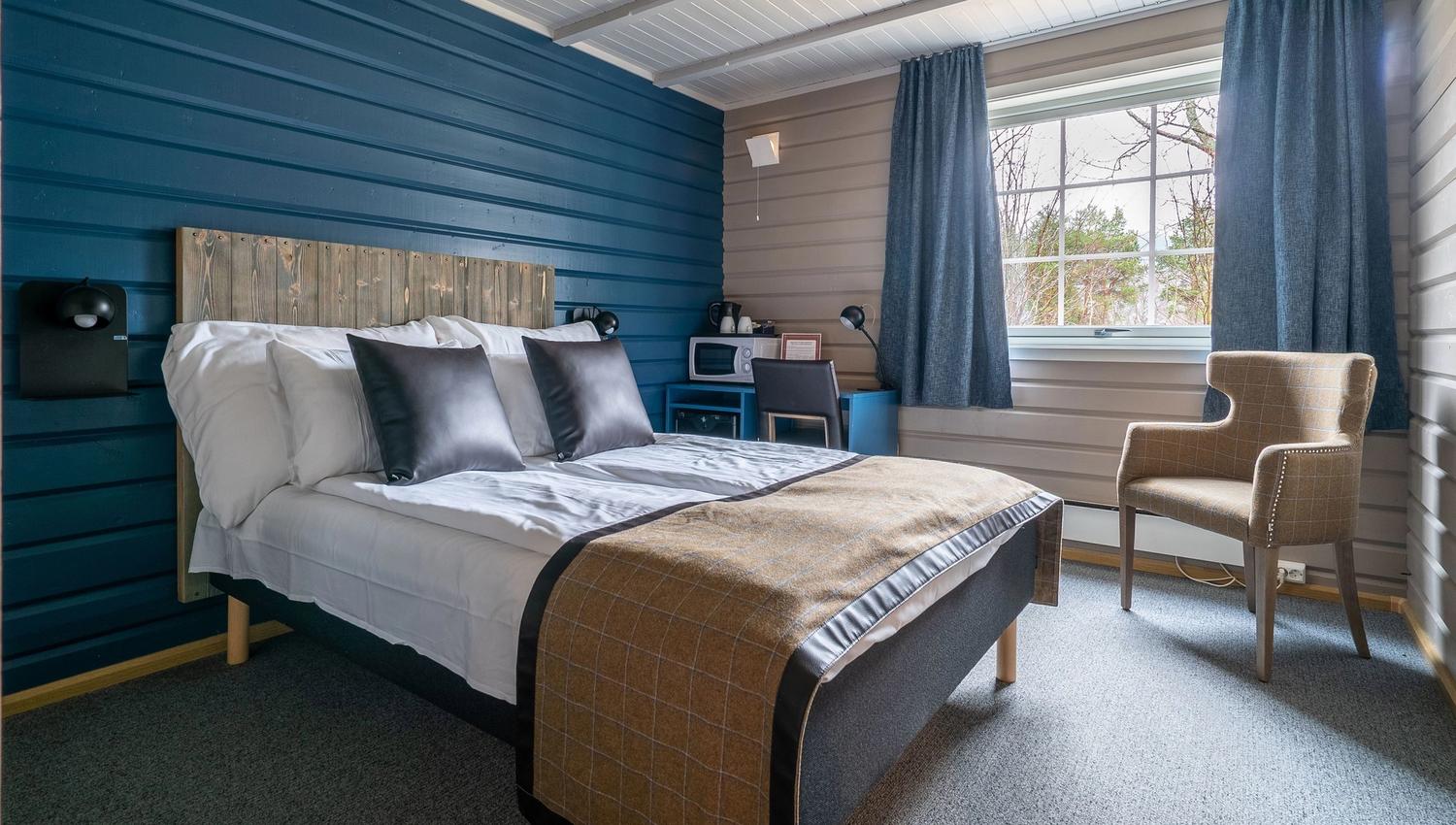 Bedroom with bed, blue curtains, desk, and two-tone walls