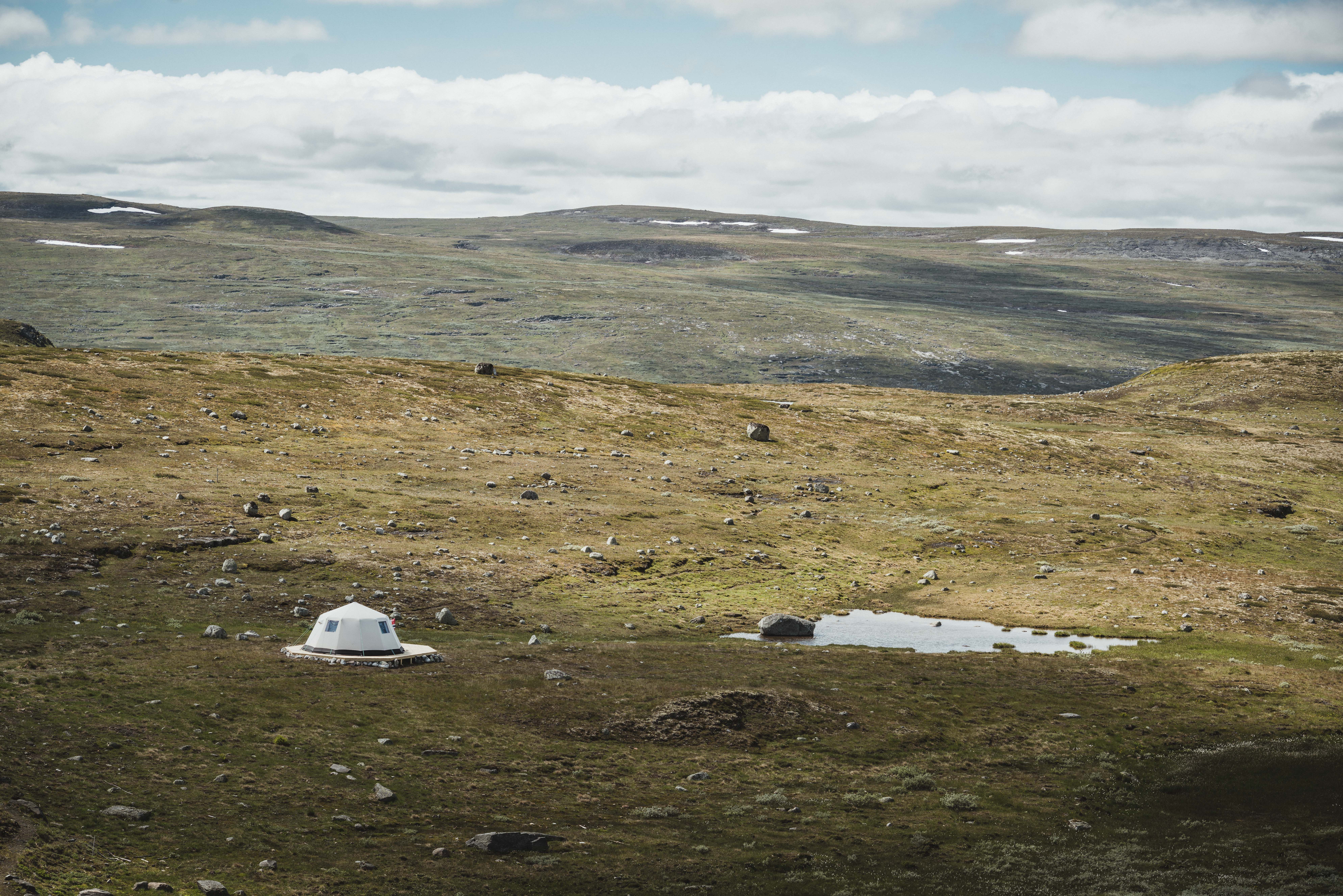 A glamping tent belonging to Dyranut Fjellstova, sitting right by a small mountain lake.