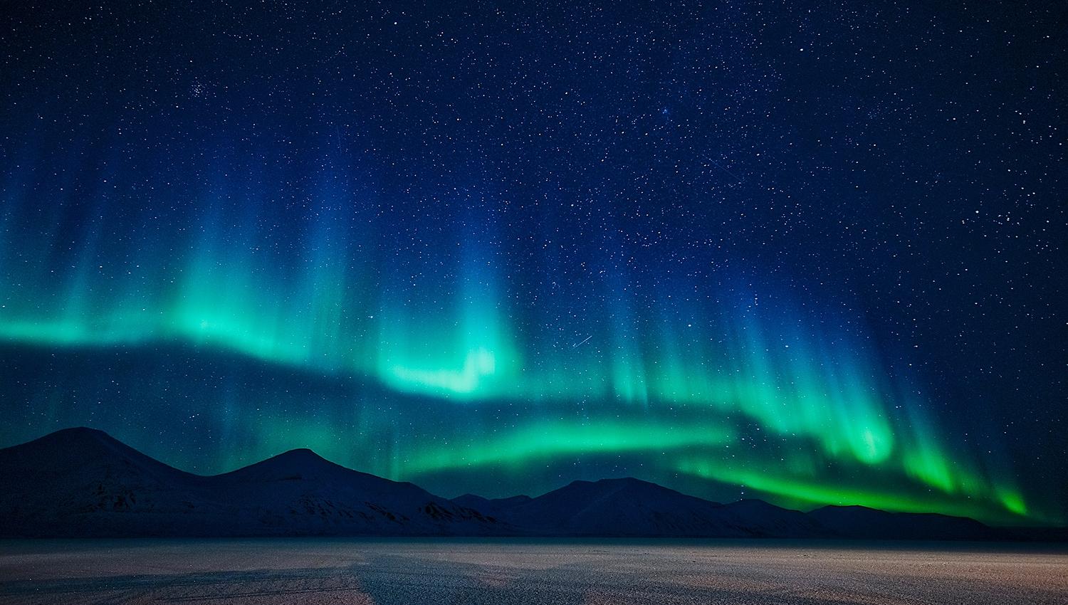 Nordlys som skinner over fjell