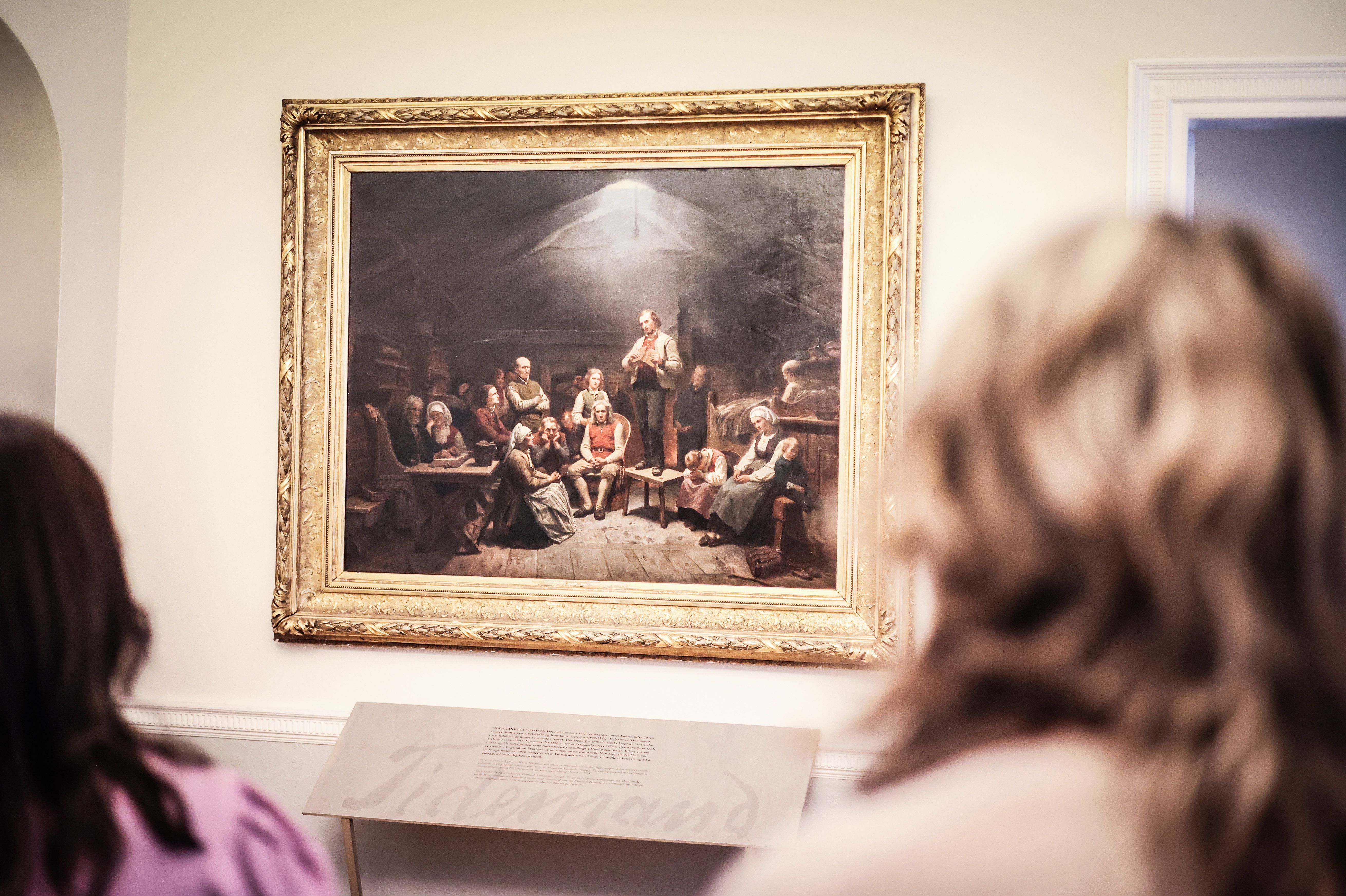 A couple is looking at the large painting ‘The Haugeans’ at the Mandal Museum, in which Adolph Tidemand depicts the followers of the lay preacher Hans