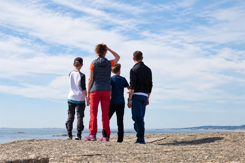 Four people standing on coastal rocks, looking out over the sea in Færder National Park.
