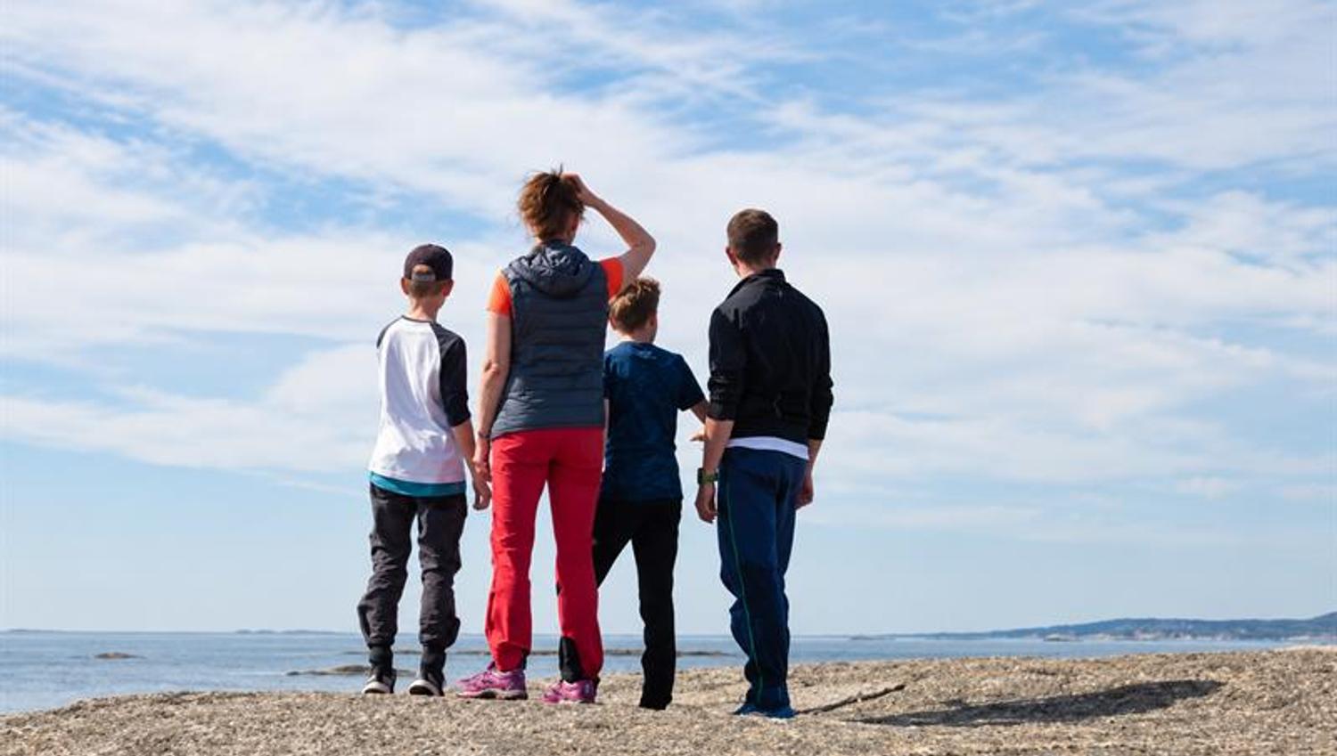 Four people standing on coastal rocks, looking out over the sea in Færder National Park.