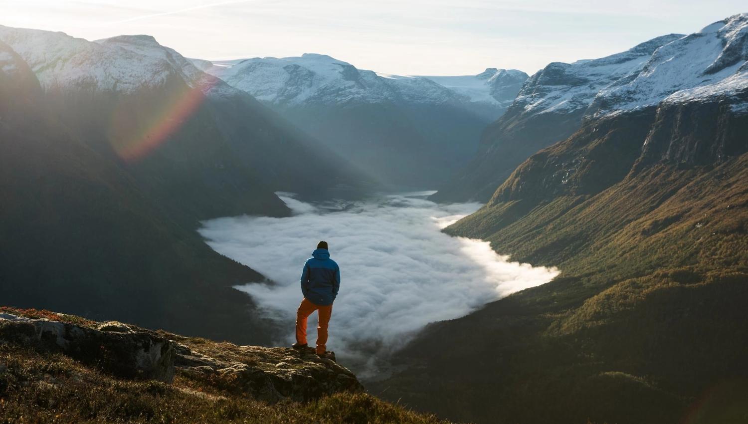 Hiker looking out over the fjord and mountain landscape from a viewpoint at Hoven.