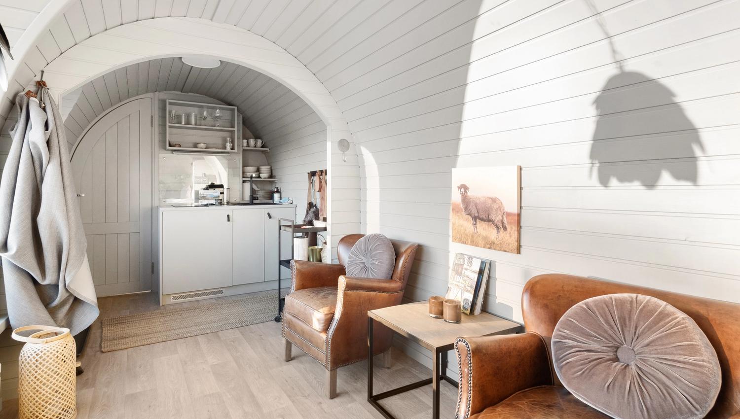 interior photo from a cabin with chairs and a bed, table and a small kitchen