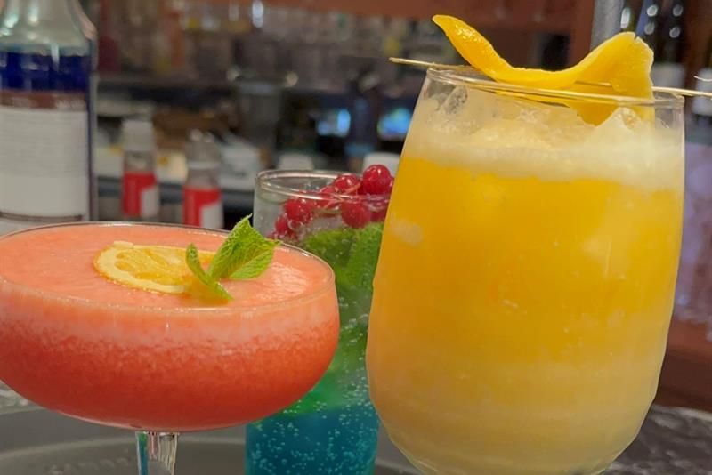 Fargerike mocktails serveres med frisk frukt og sitrus ved baren.