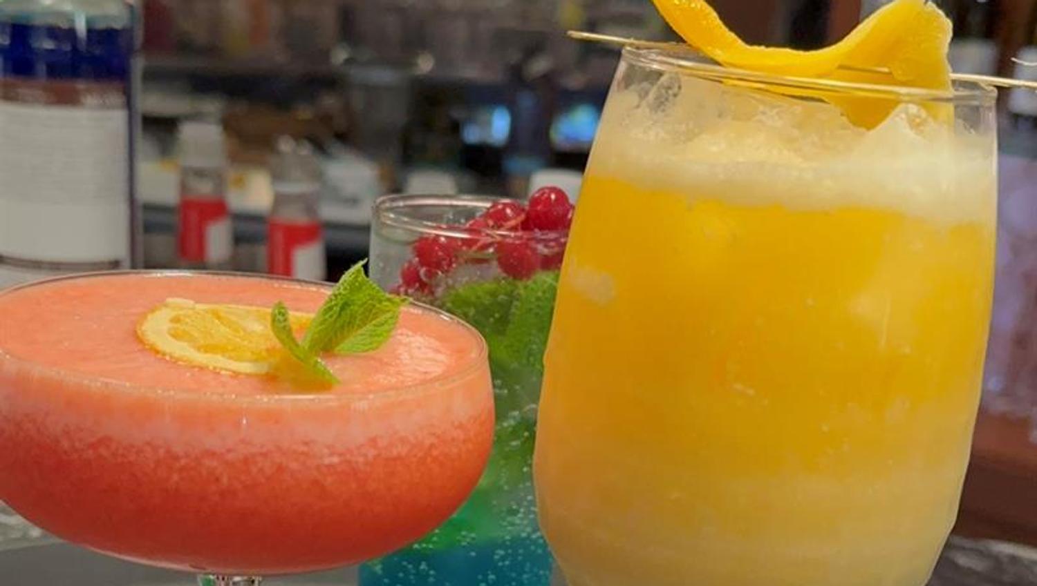 Fargerike mocktails serveres med frisk frukt og sitrus ved baren.