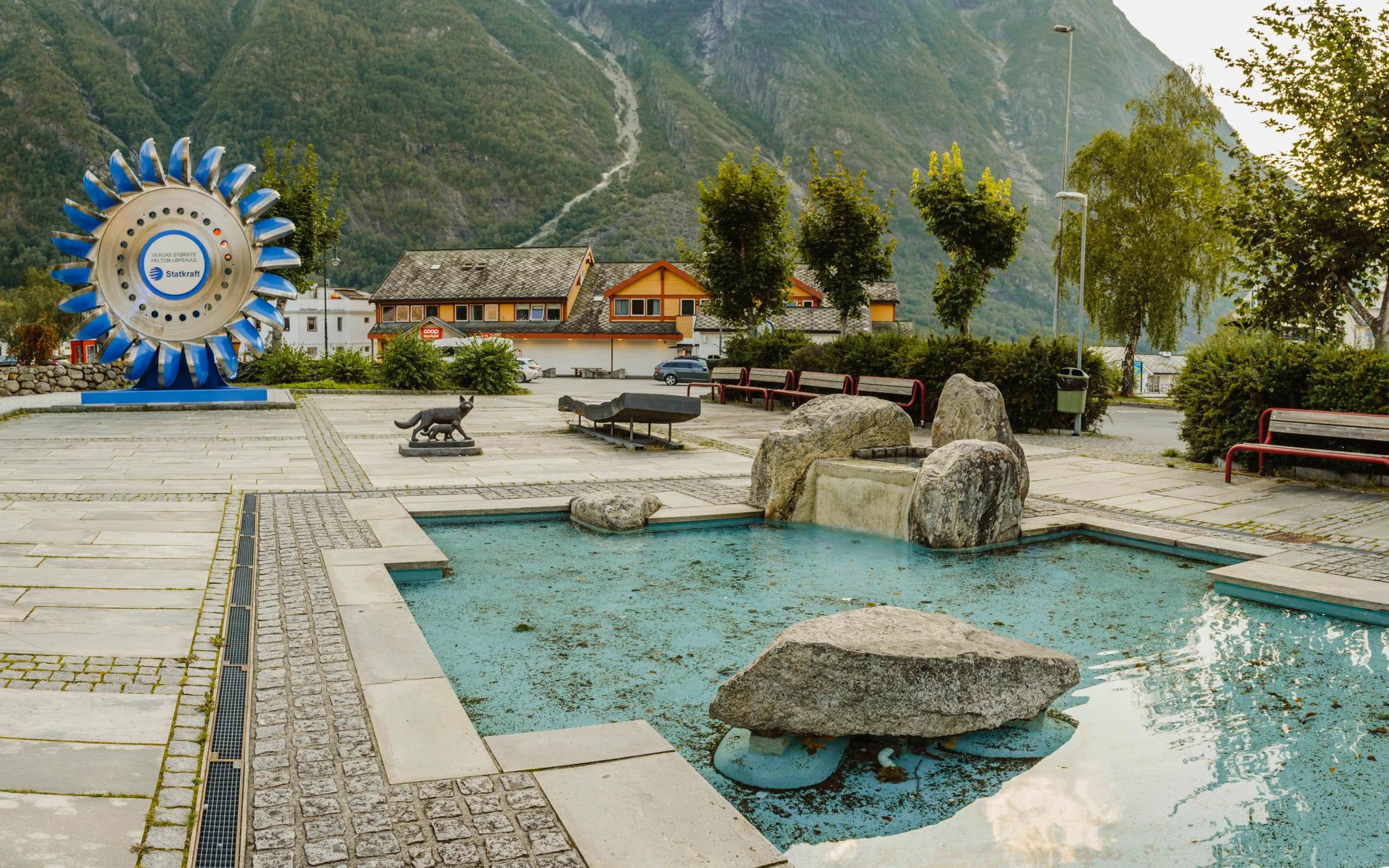 The sculpture park with it's small pool in the middle and the large pelton wheel in the background.