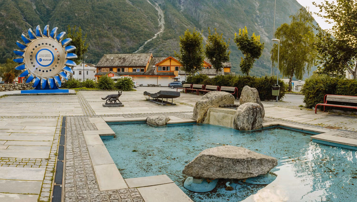 The sculpture park with it's small pool in the middle and the large pelton wheel in the background.