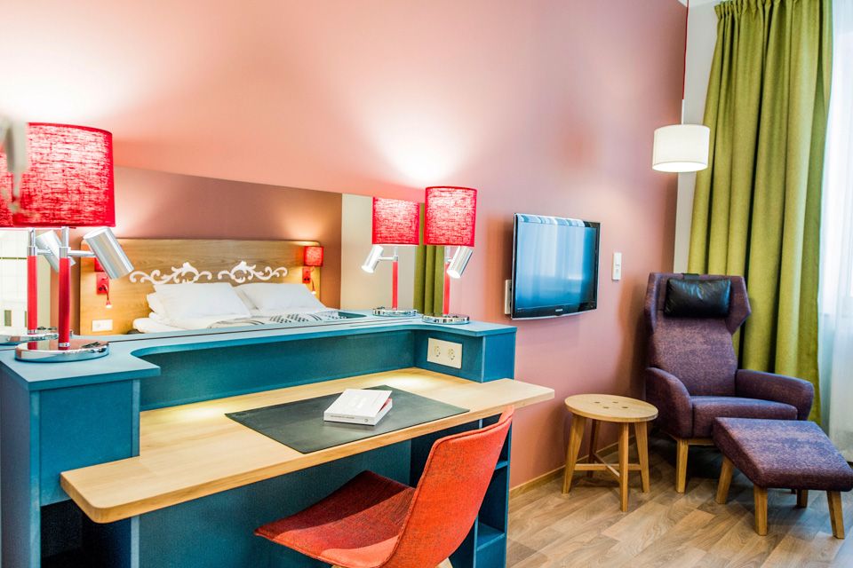 Skrivebord på gjesterom. Rød stol og røde lampeskjerm. Hotell Bondeheimen, Oslo. Foto