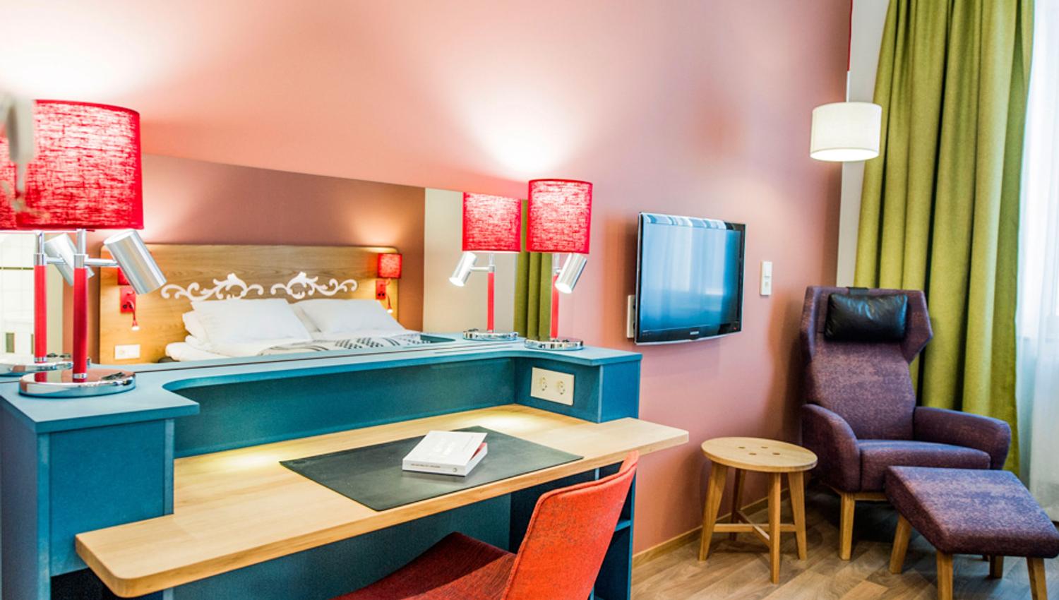 Skrivebord på gjesterom. Rød stol og røde lampeskjerm. Hotell Bondeheimen, Oslo. Foto