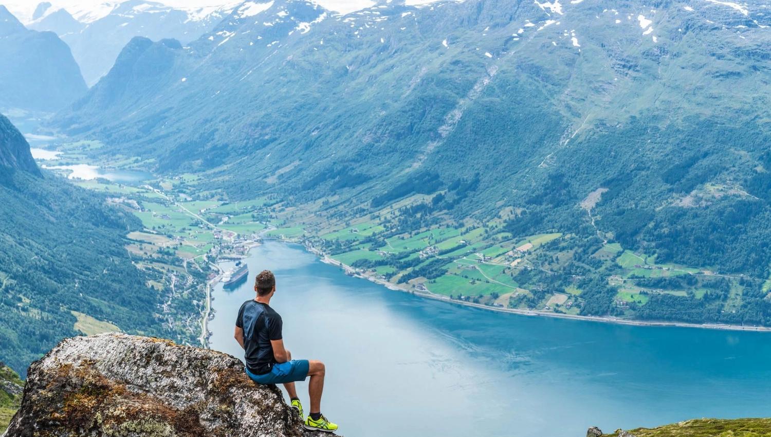 Hiker taking in the panoramic view of Nordfjord and the surrounding mountains from Hoven.