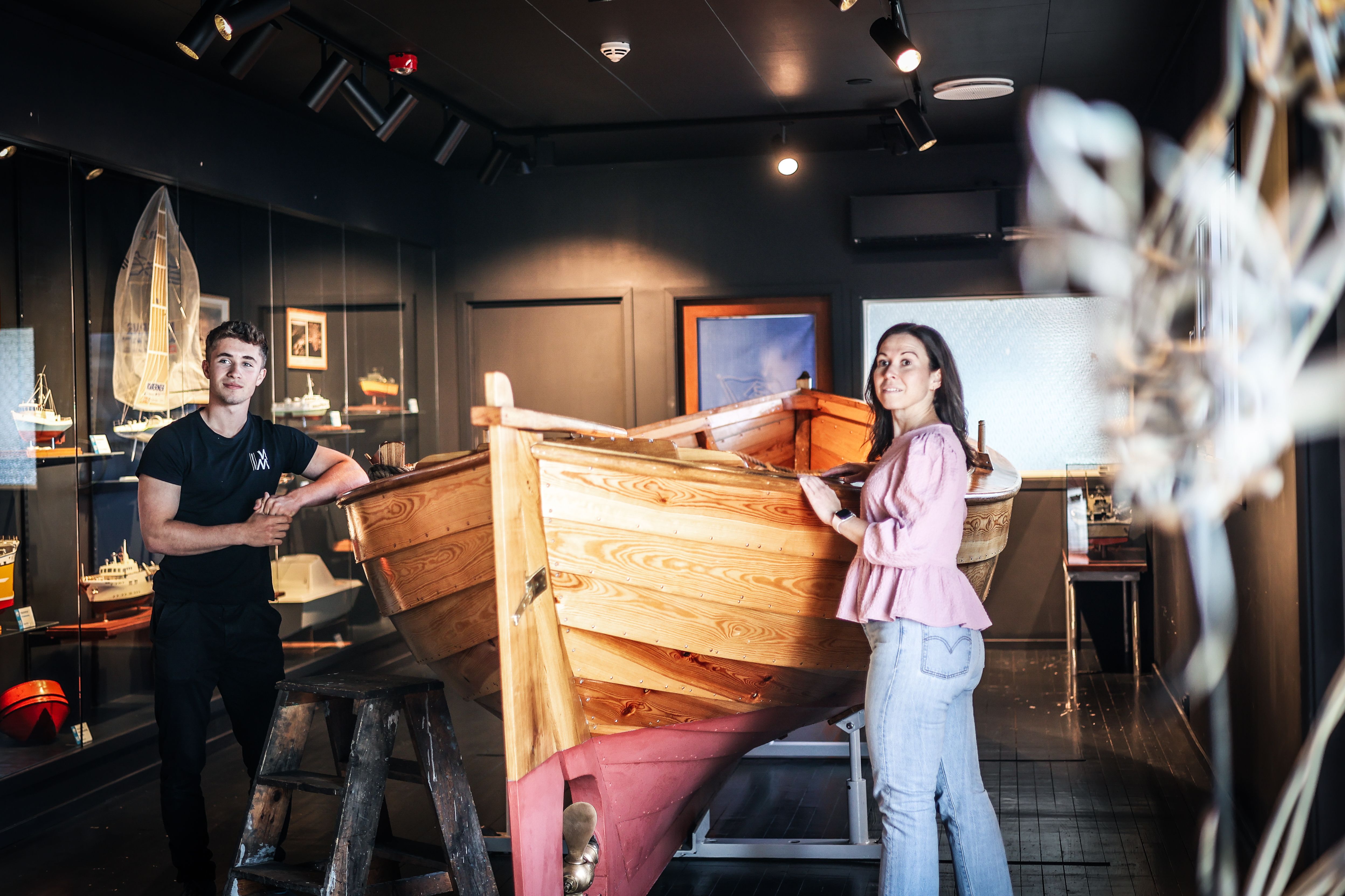 A guide and a lady are looking at a wooden boat.