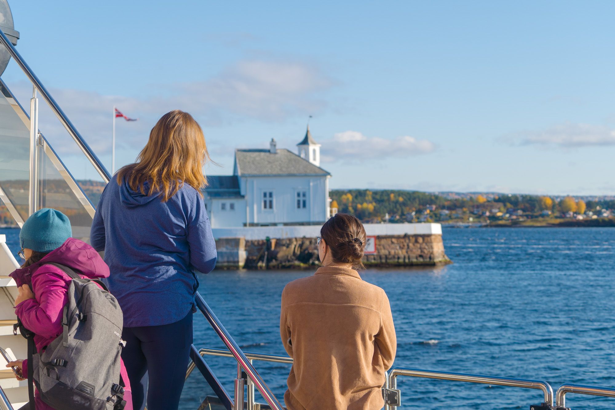 Personer som ser på et fyrtårn i fjorden fra båten
