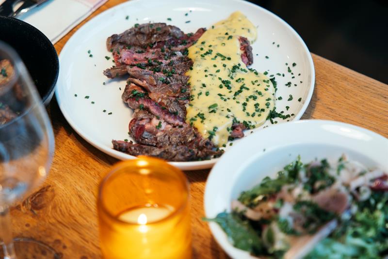 Saftig biff med bearnaisesaus og frisk salat servert på rustikt trebord.