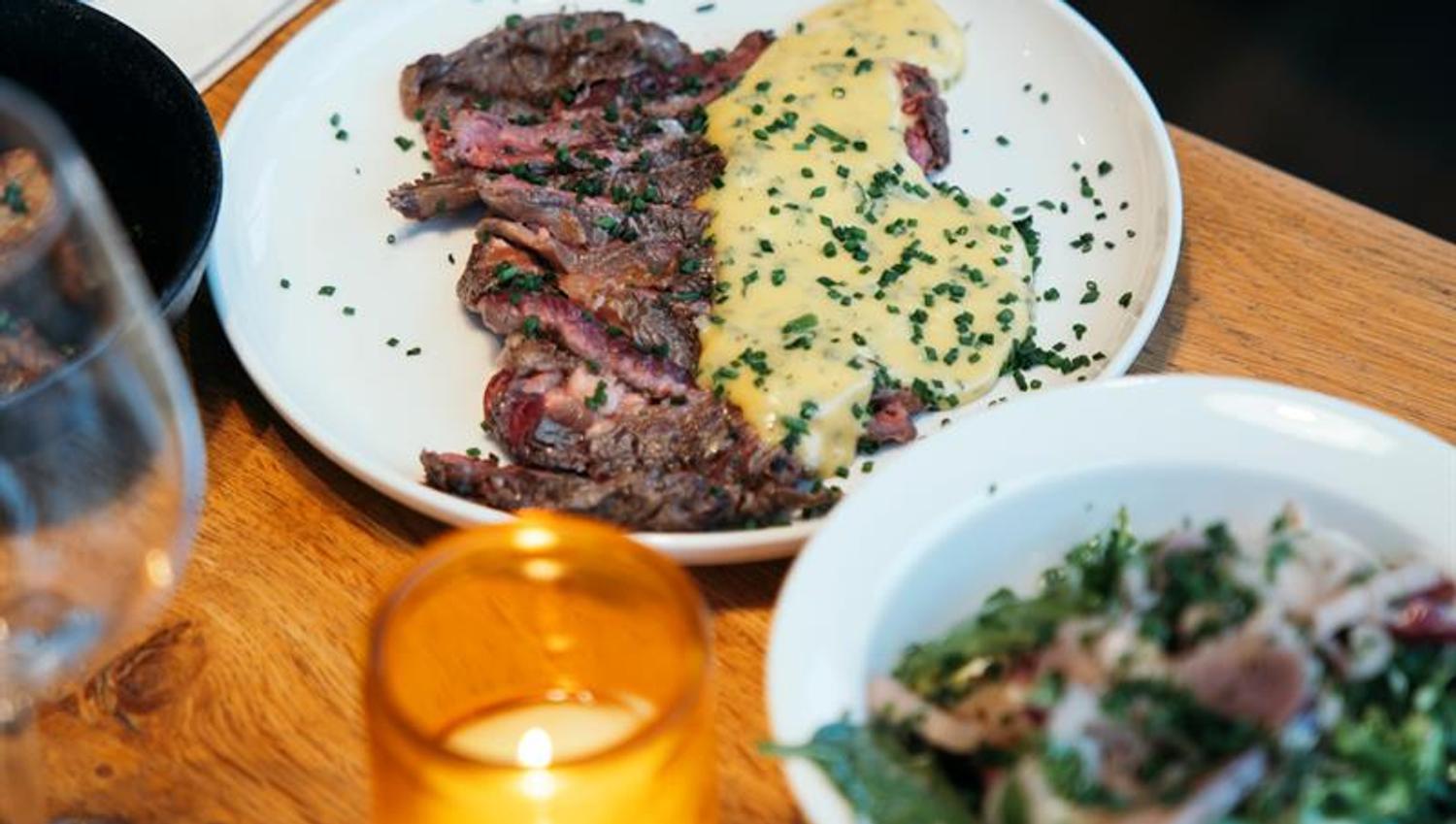 Saftig biff med bearnaisesaus og frisk salat servert på rustikt trebord.