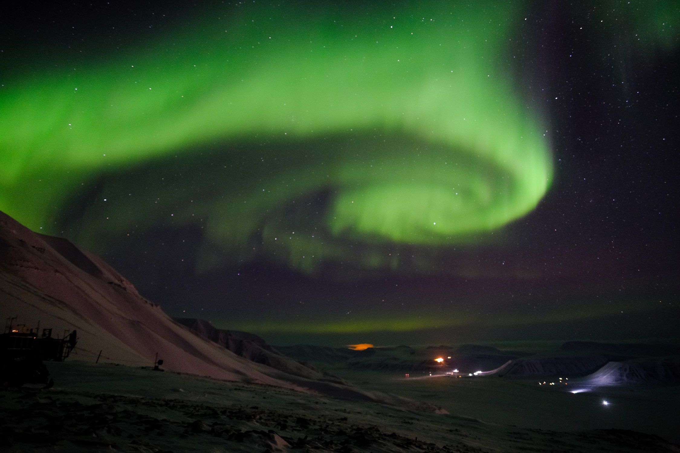 A whirling stream of northern lights in the skies above a valley