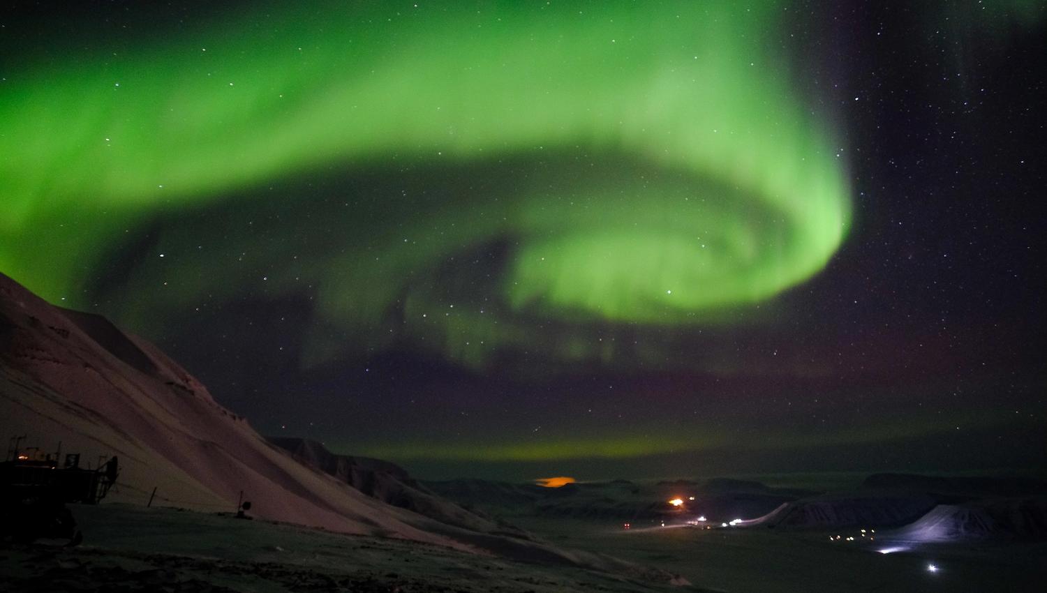 A whirling stream of northern lights in the skies above a valley