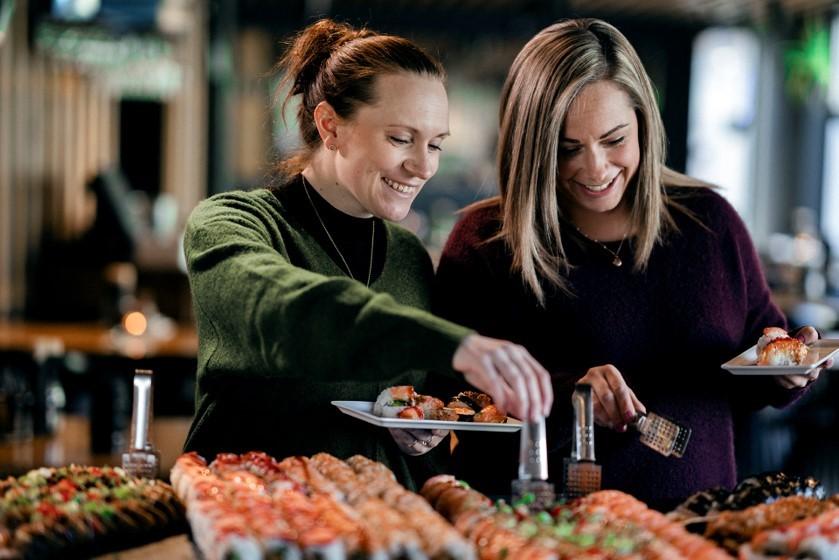 Smilende gjester som forskyner seg av sushi