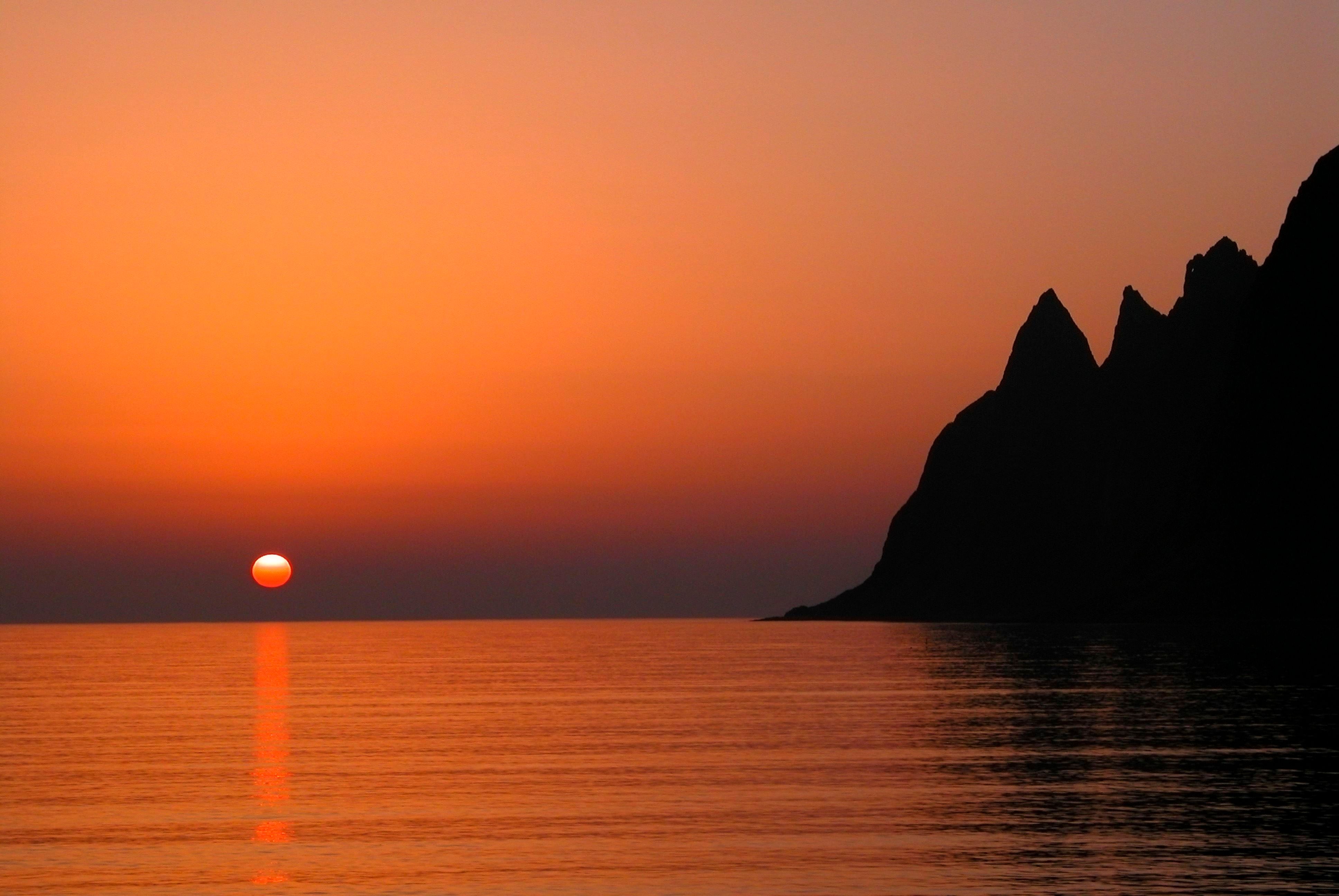 Midnattssolen over havet og fjellene på Senja