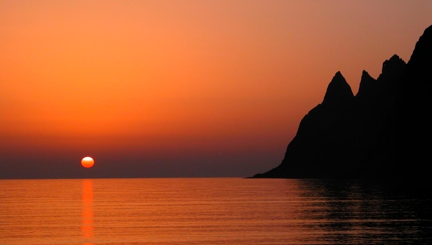 Midnattssolen over havet og fjellene på Senja