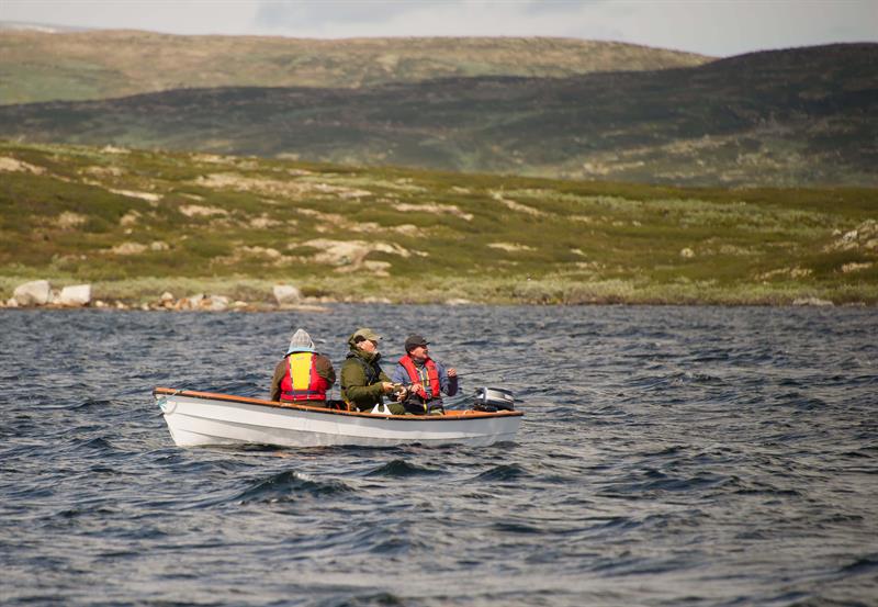 Drei Personen angeln von einem kleinen Boot aus auf dem See Halnefjorden.