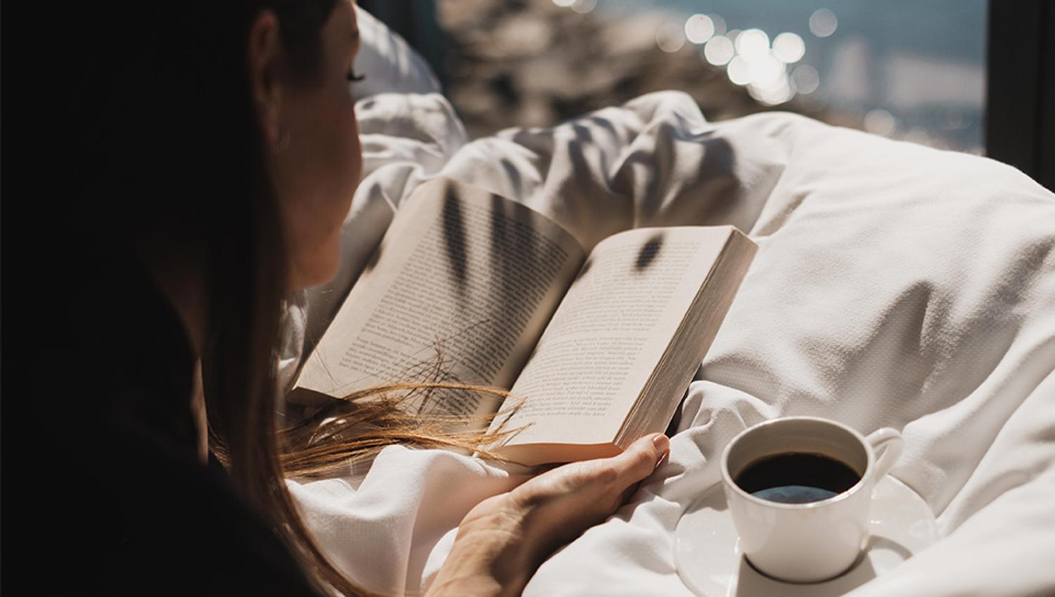 Person reads a book with a cup of coffe