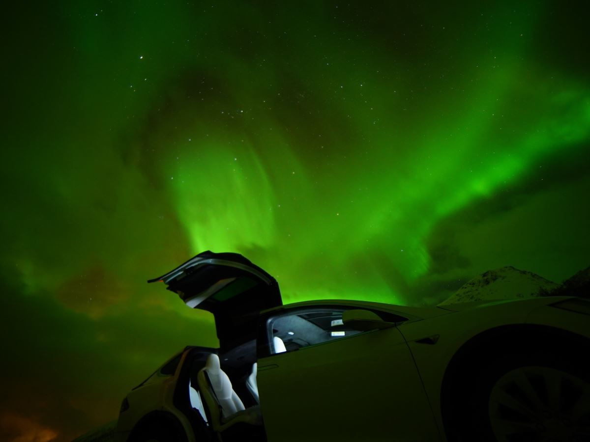 An open car door with the northern lights in the background