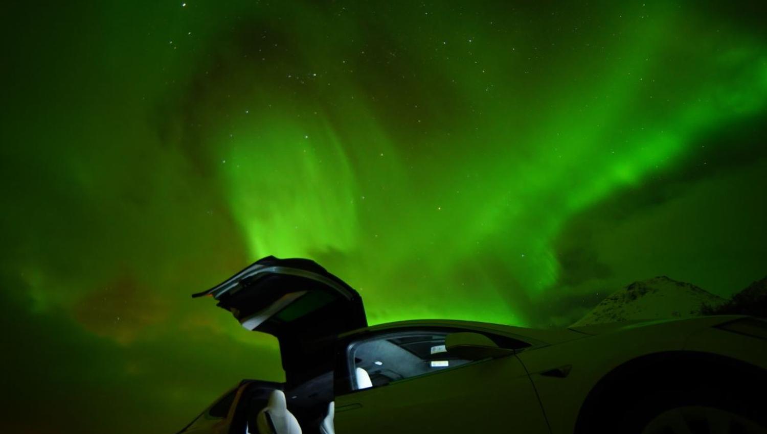 An open car door with the northern lights in the background