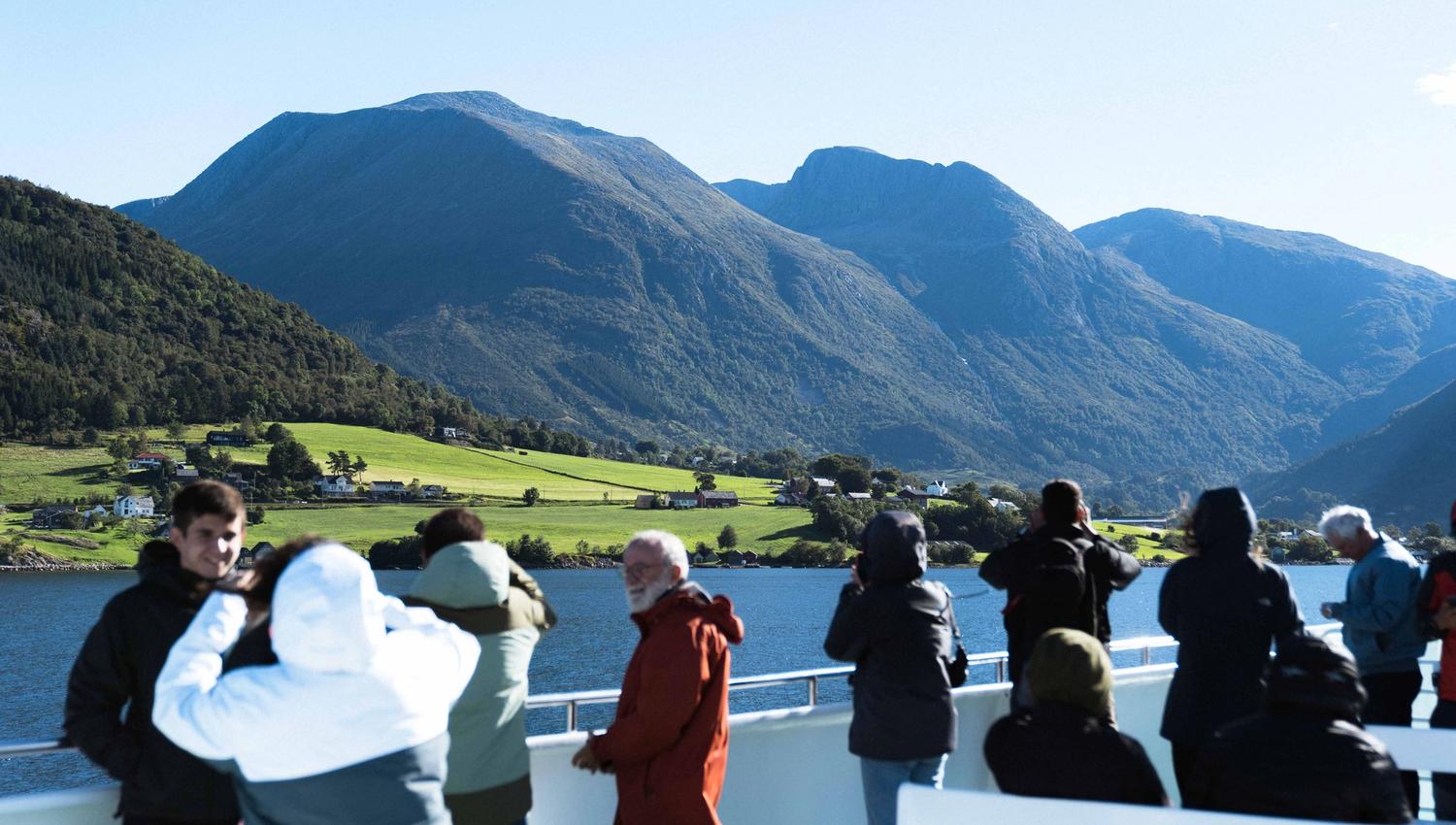 Tourists on the deck of Hardangerfjordekspressen enjoying the view of the fjord and mountains in Hardanger.