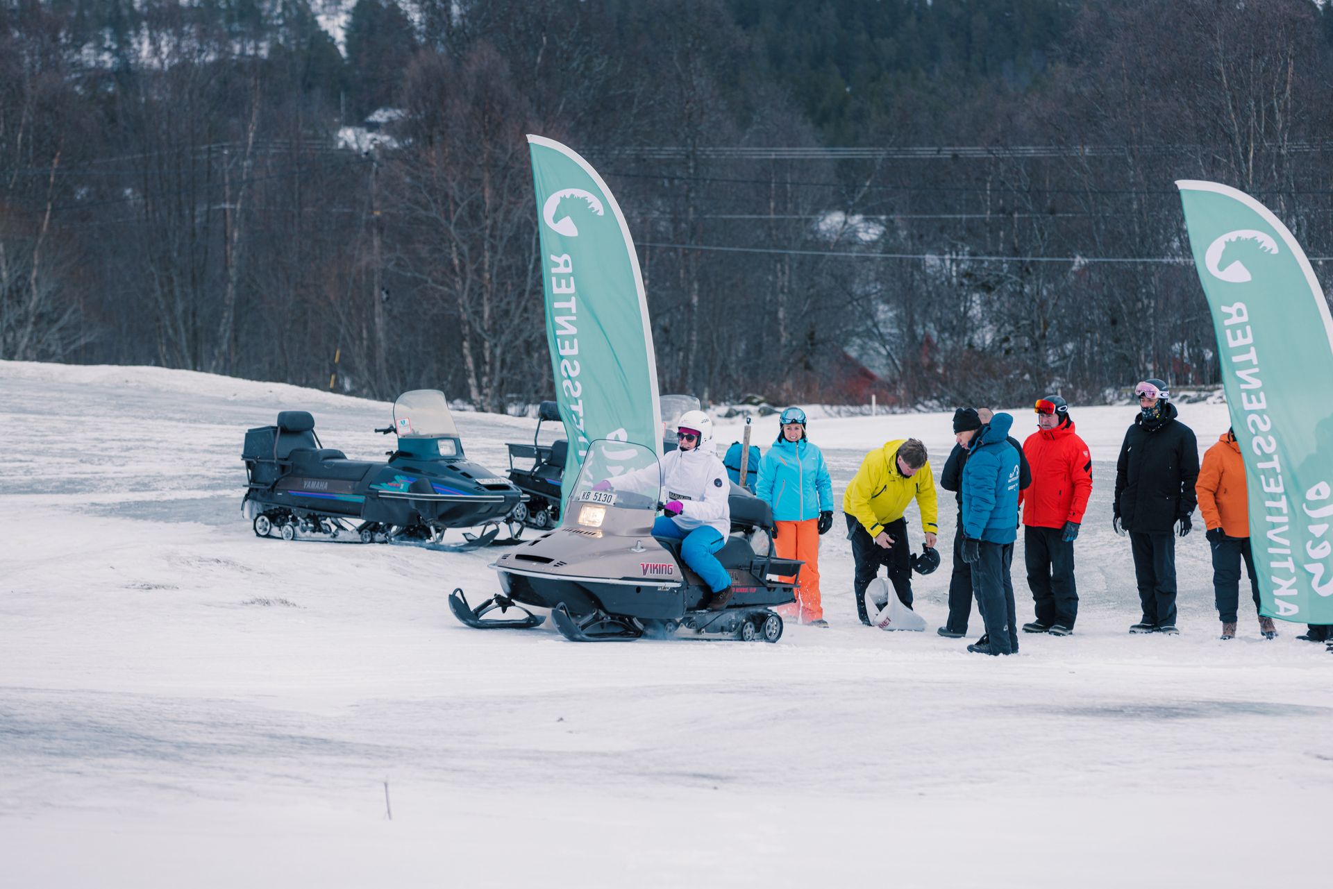 A group of people are chatting and enjoying themselves after a great snowmobile tour.