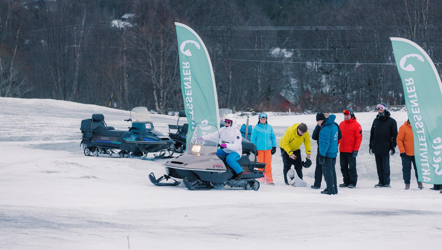 A group of people are chatting and enjoying themselves after a great snowmobile tour.