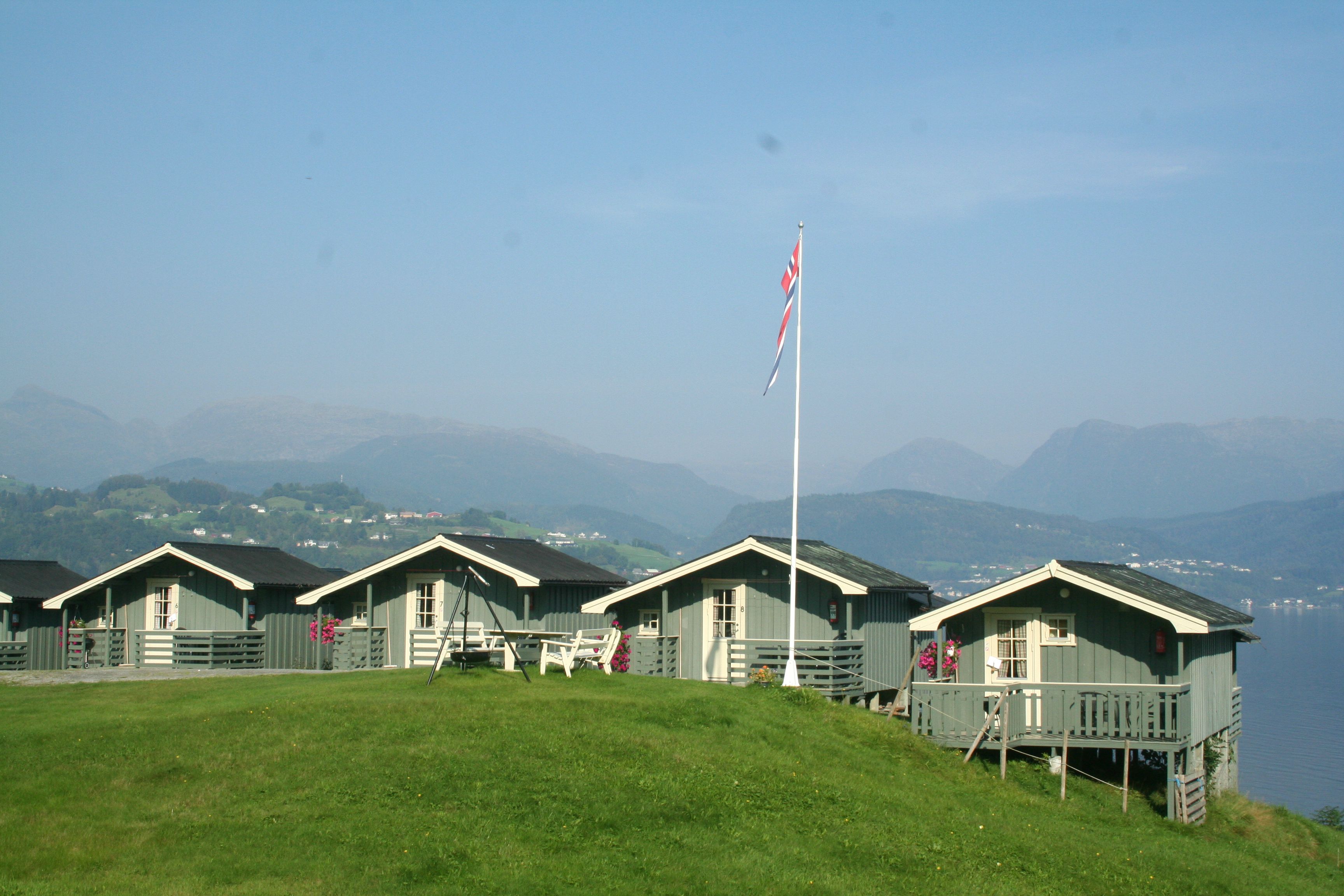 Rows of cabins at Oddland Camping with panoramic views of the fjord and mountains in Hardanger.