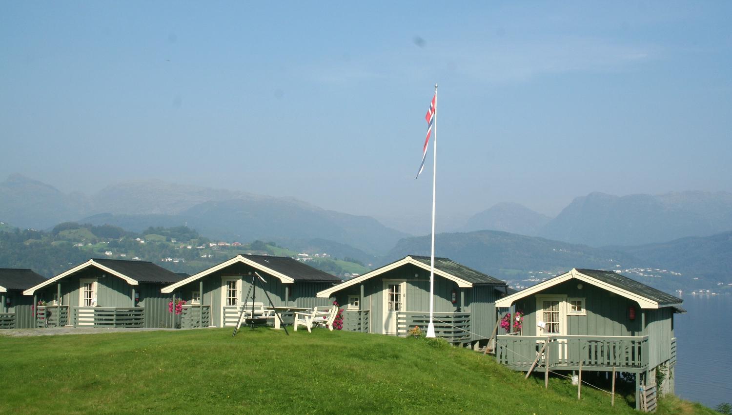 Rows of cabins at Oddland Camping with panoramic views of the fjord and mountains in Hardanger.