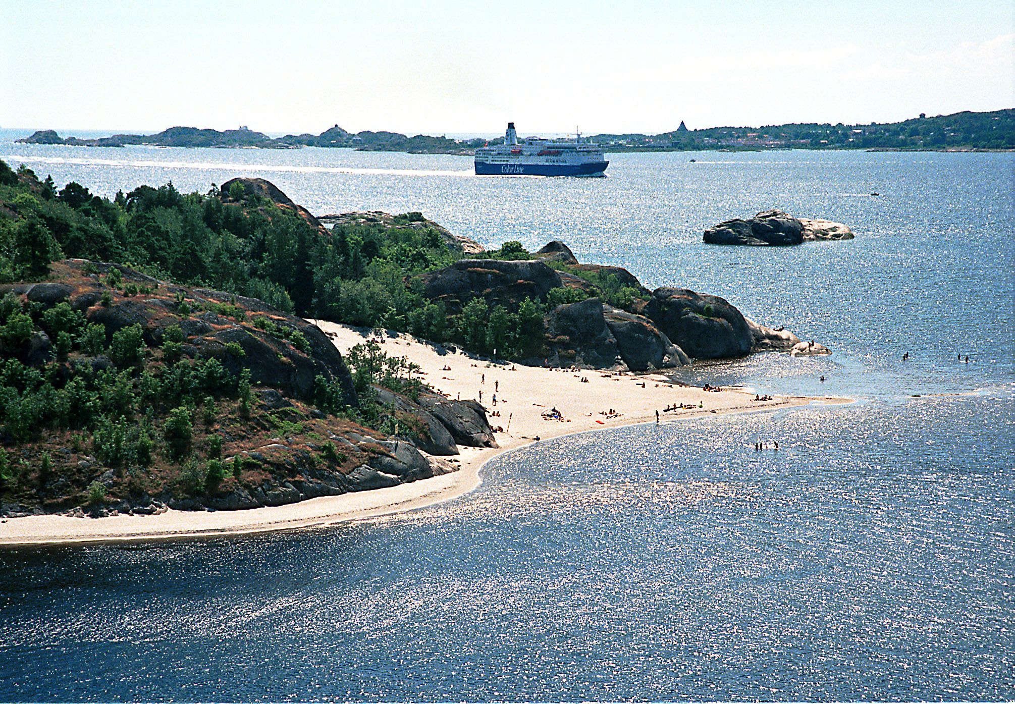 Hav, sandstrand og grønne trær på fjell
