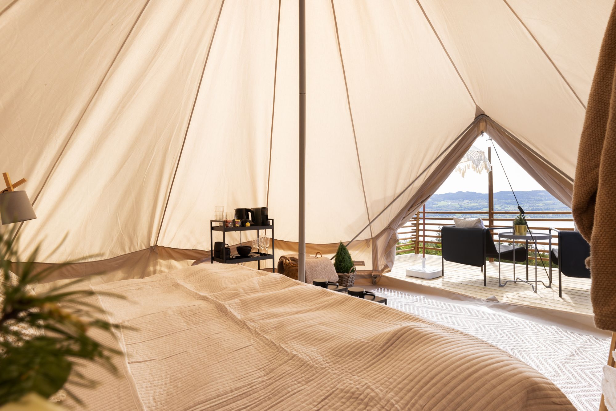 View of the tent with the bed, table and outside view. 