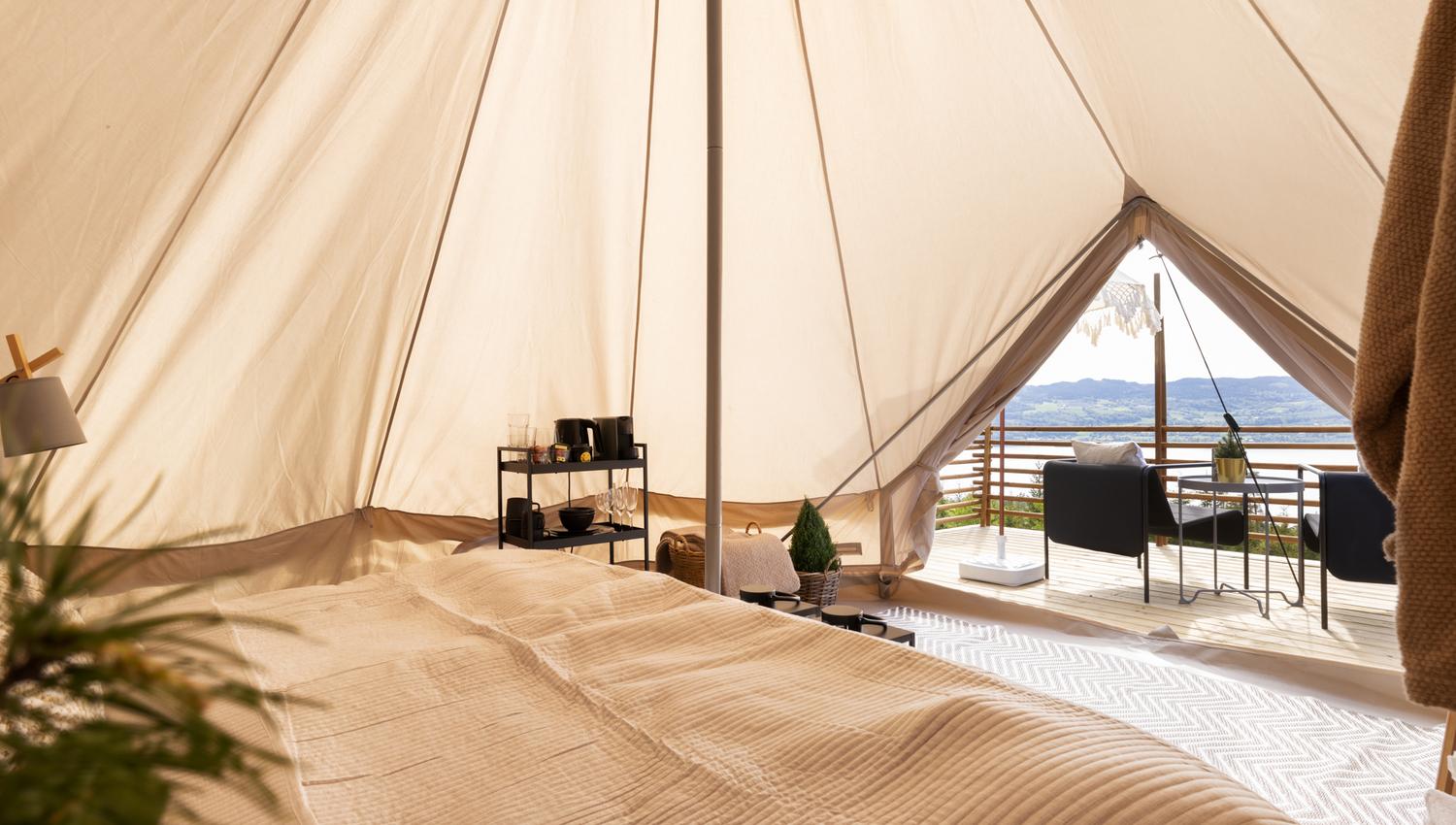 View of the tent with the bed, table and outside view.