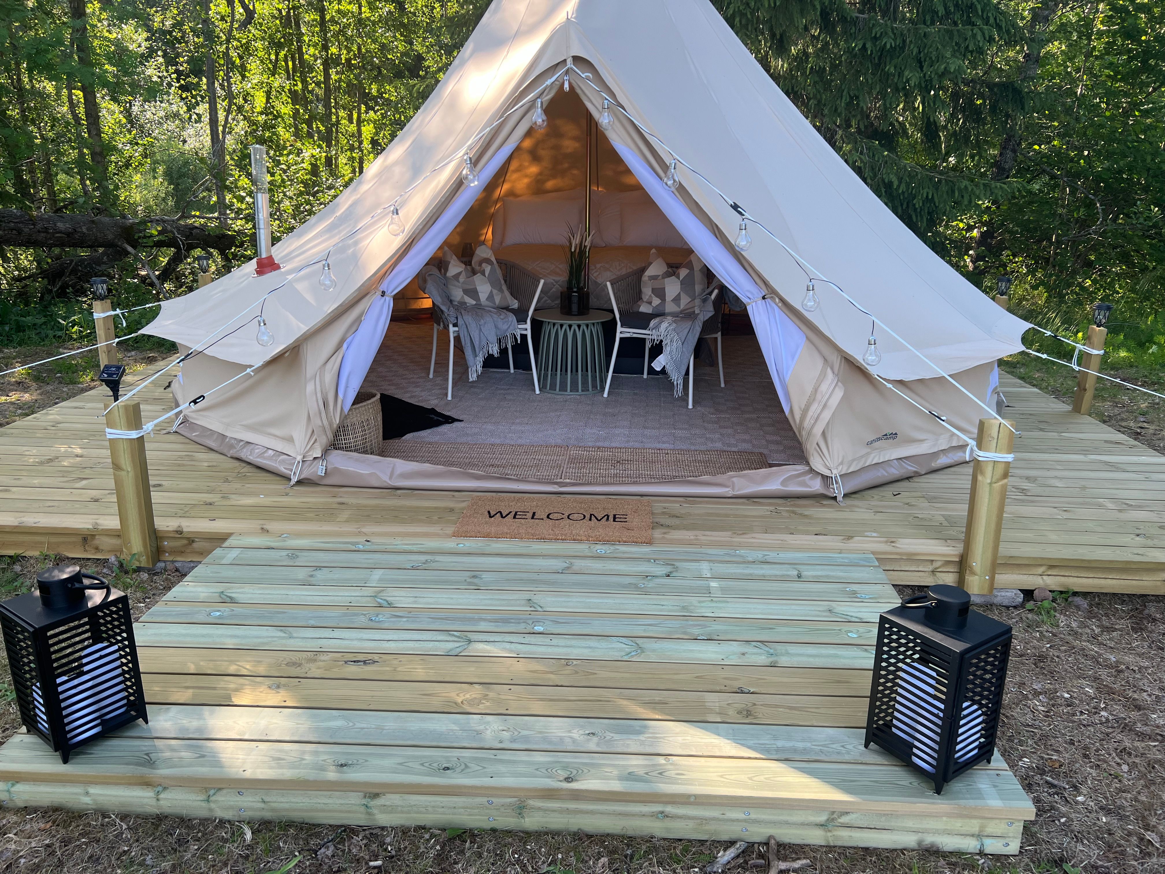 Platting with lanterns where the tent is open so you can see into the tent - with a double bed and a pleasant atmosphere