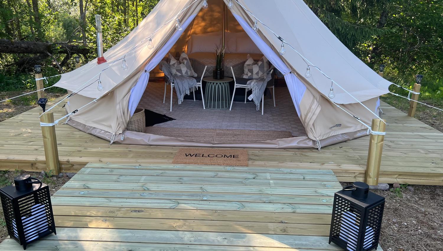 Platting with lanterns where the tent is open so you can see into the tent - with a double bed and a pleasant atmosphere