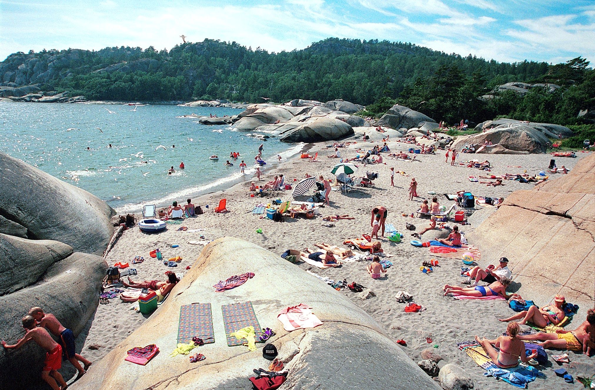 Mennesker på sandstrand og svaberg