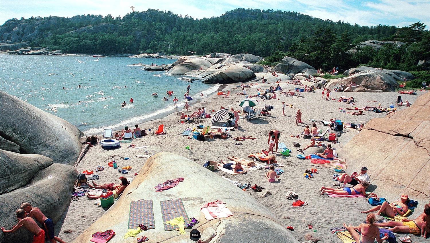 Mennesker på sandstrand og svaberg