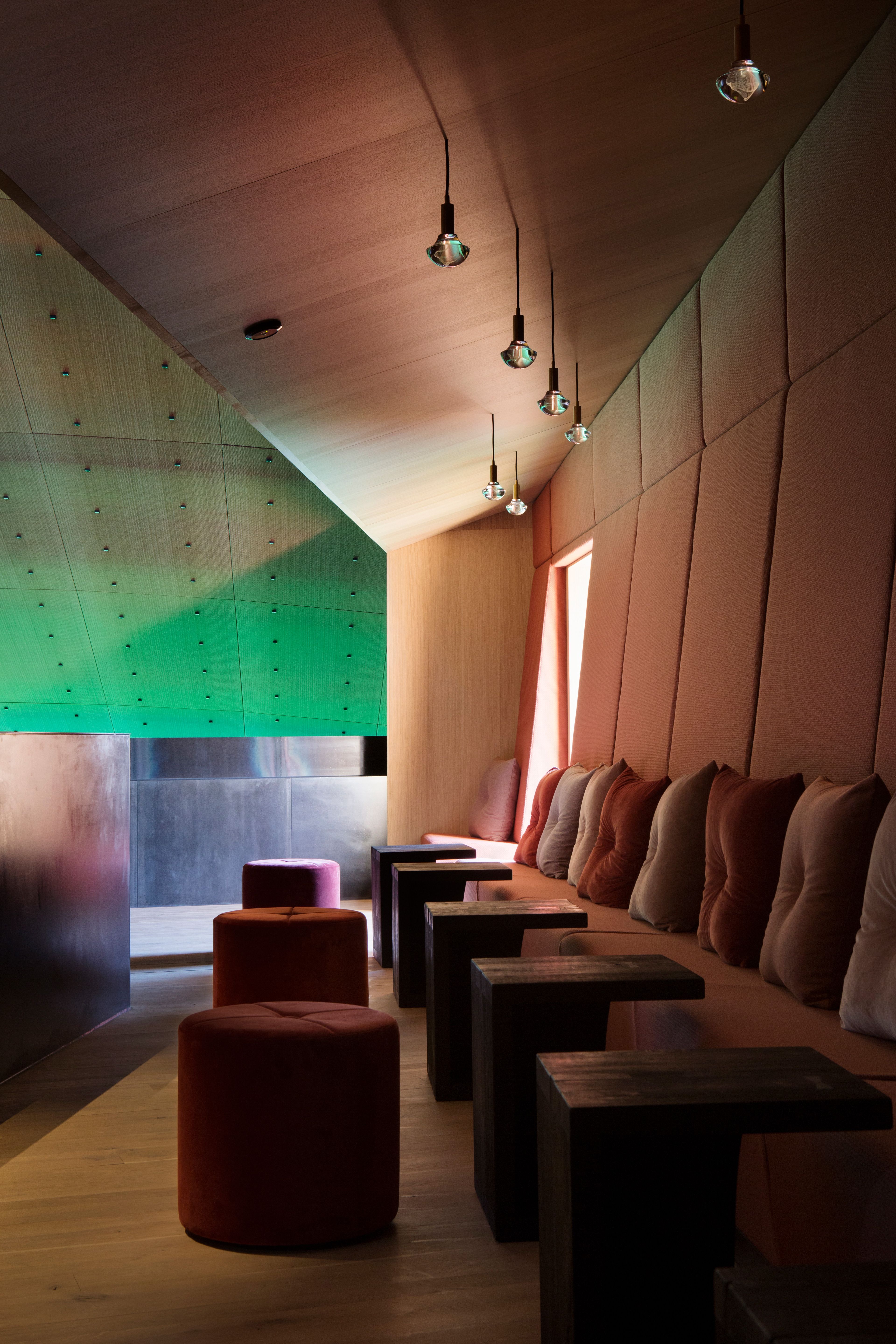 Sofa with small tables between the seats. Green lighting on the ceiling, cozy atmosphere.