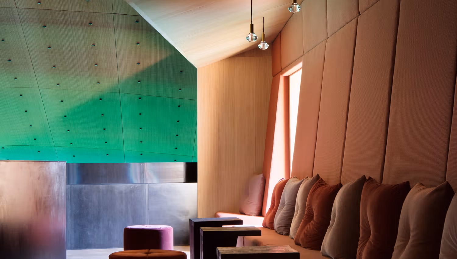 Sofa with small tables between the seats. Green lighting on the ceiling, cozy atmosphere.