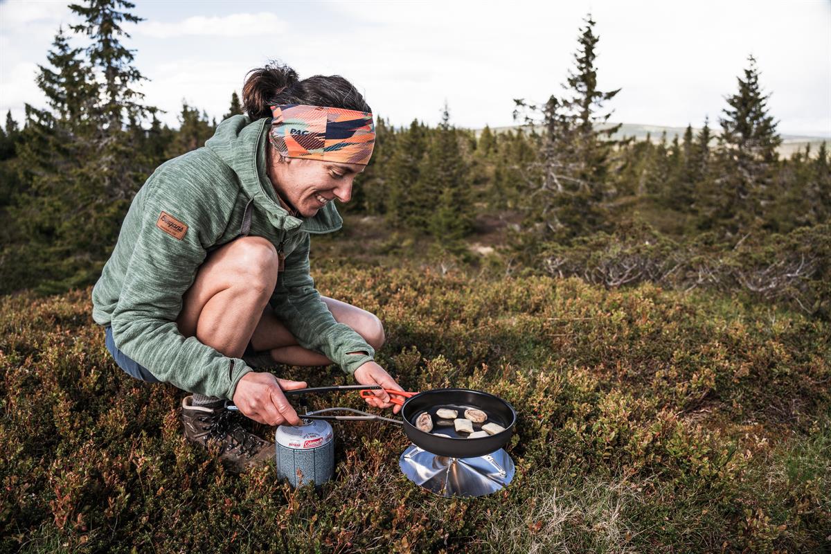 Person cooking on a camping stove in nature