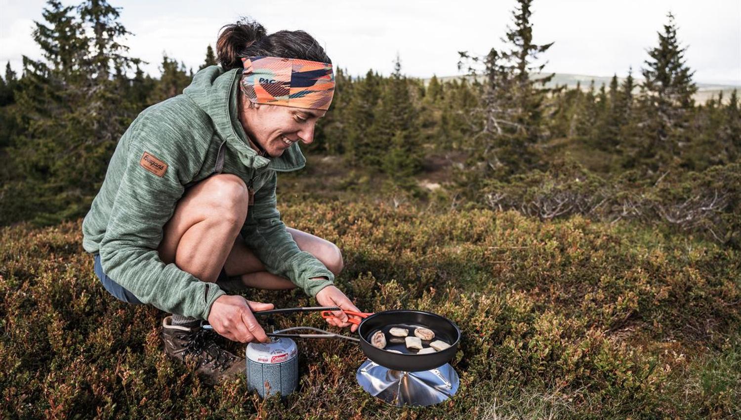 Person cooking on a portable stove in the mountains