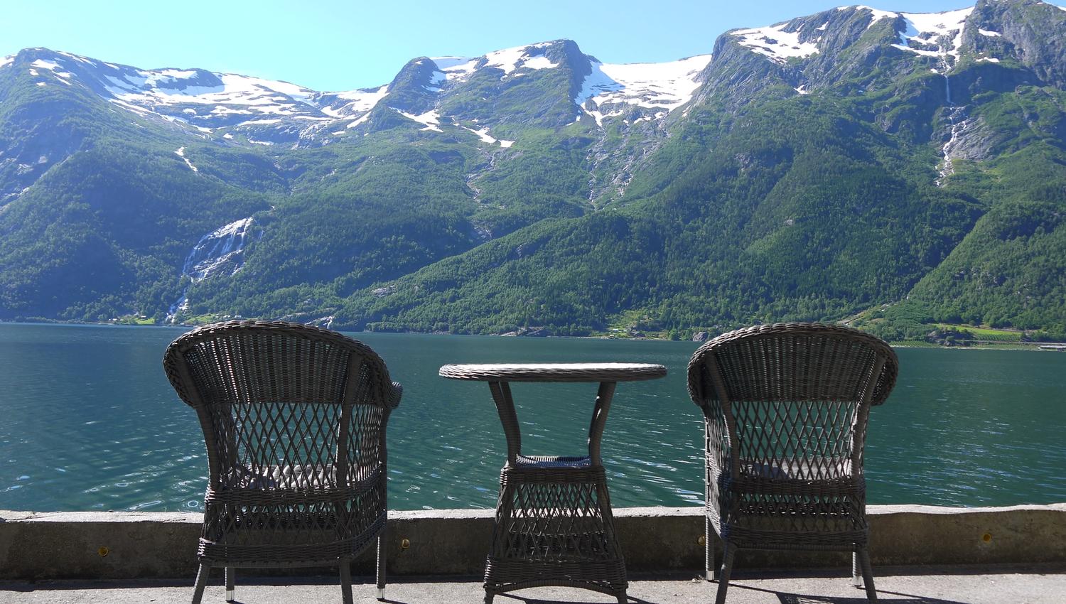 Two chairs and a table on the pier at Stana Farm – the perfect spot for morning coffee with a panoramic fjord view.