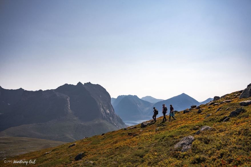 Three guests hiking with mountains in the background
